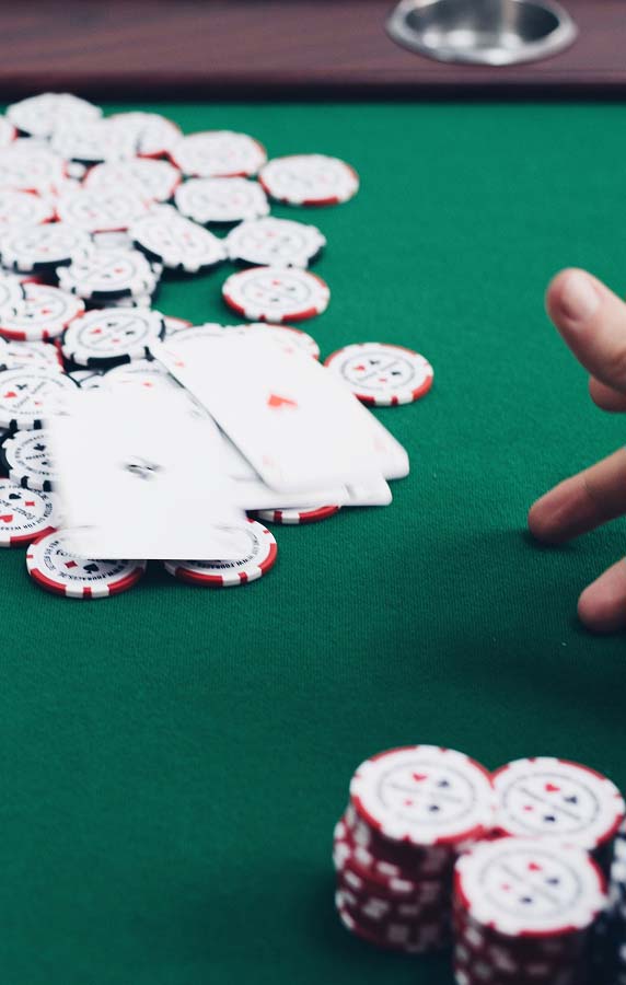 Hand wirft Pokerkarten in der Unschärfe auf einen Pokertisch voller Poker Chips