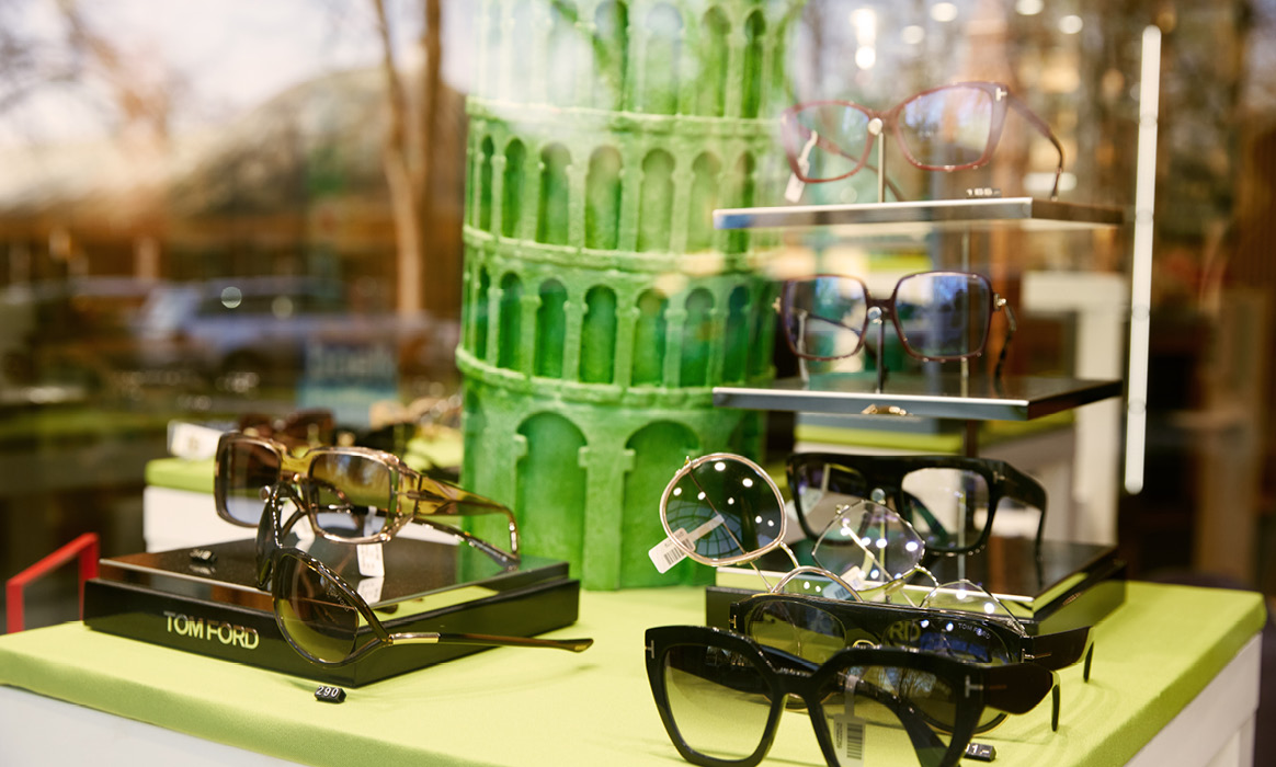 Brillenpräsentation im Schaufenster von Optik Boelke mit mehreren Brillenfassungen auf Podesten und dekorativen Elementen.